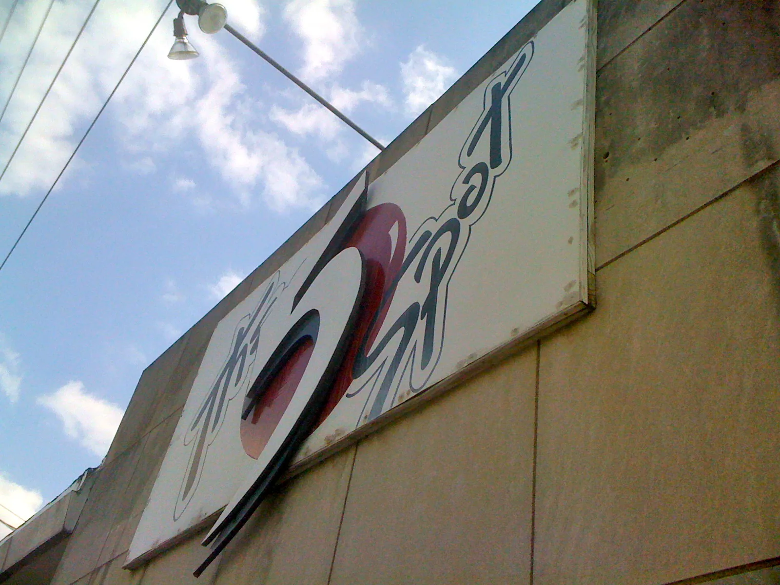 The 5 Spot's white sign, with a large stylized 5 over a red circle, seen from below against a blue sky